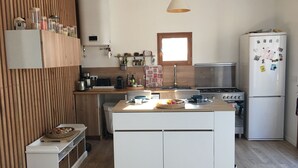 Eine kompakte Küche mit einer zentralen Kochinsel, Holzvertäfelung, einem eingebauten Herd und einem Kühlschrank mit Magneten.