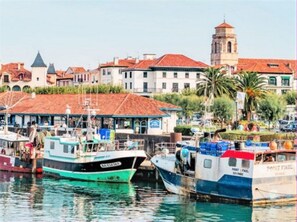 Stunning harbor views with boats docked at a picturesque pier, surrounded by historic buildings with red-tiled roofs.