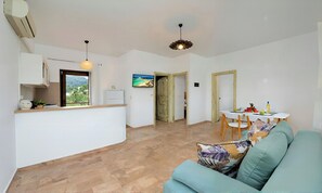 A modern living space with a kitchen, dining area, and seating area. - Plaisir Beachside Apts (Agios Nikolaos)