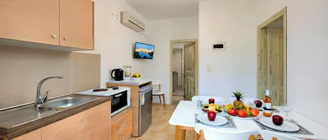 A compact kitchen with a sink, stove, and a dining area with a table set for two.