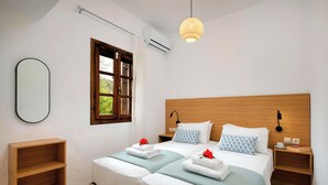 A double bed with a wooden headboard, two bedside tables with lamps, a small shelf, and a window with curtains.