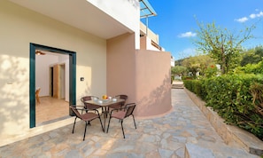 An outdoor seating area with stone flooring, a table, and chairs. - Plaisir Beachside Apts (Agios Nikolaos)