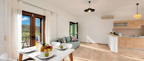 Un comedor moderno con una mesa dispuesta para dos personas, un sofá y una cocina al fondo.