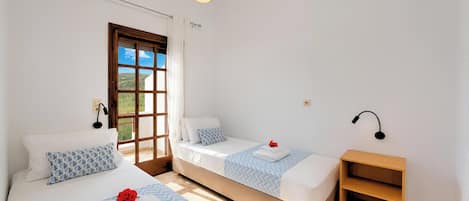 Un dormitorio con dos camas, una ventana con vistas, una mesita de noche y una lámpara colgante.