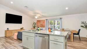 Une cuisine moderne dotée d’un îlot central, d’un lave-vaisselle encastré et d’un coin repas avec une table et des chaises.