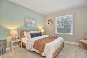 Une chambre à coucher avec un lit, des lampes de chevet, une fenêtre et une chaise.