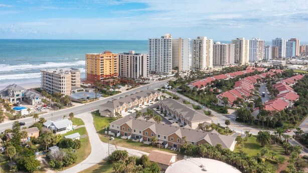 Un quartier résidentiel situé sur la côte, caractérisé par de grands immeubles, un port de plaisance et une plage.