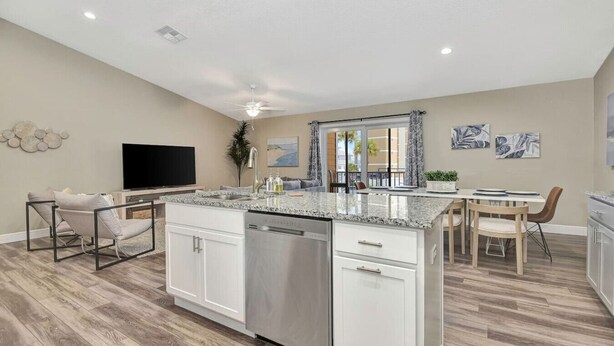 Una cocina moderna con lavavajillas, un comedor con mesa y sillas, y un televisor de pantalla plana.