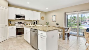 A modern kitchen with white cabinetry, stainless steel appliances, and a granite countertop. - Beach Bliss, 5 MIN to BEACH-Game Room, Parking, AC (Daytona Beach Shores)