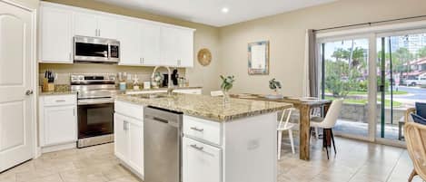 A modern kitchen with white cabinetry, stainless steel appliances, and a granite countertop.