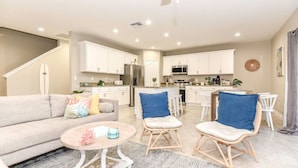 A modern living room with a sofa, two chairs, a coffee table, and a kitchen in the background. - Beach Bliss, 5 MIN to BEACH-Game Room, Parking, AC (Daytona Beach Shores)
