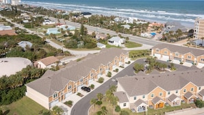 A coastal residential area with a row of townhouses, a road, and a view of the ocean. - Beach Bliss, 5 MIN to BEACH-Game Room, Parking, AC (Daytona Beach Shores)