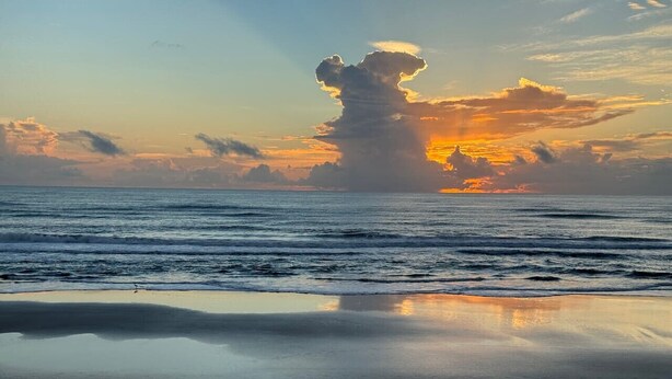 A beach with calm water and a sunset. - Beach Bliss, 5 MIN to BEACH-Game Room, Parking, AC (Daytona Beach Shores)