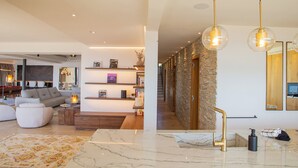 Un salon moderne avec un canapé, une table basse et des étagères. Un escalier mène à un autre niveau.