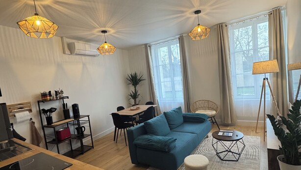 A modern living room with a blue sofa, wooden flooring, and pendant lighting. - Facing the castle & Air-conditioned ~ El Castillo ~ (Surgères)