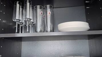 A kitchen with shelves holding clear glasses, plates, and bowls.