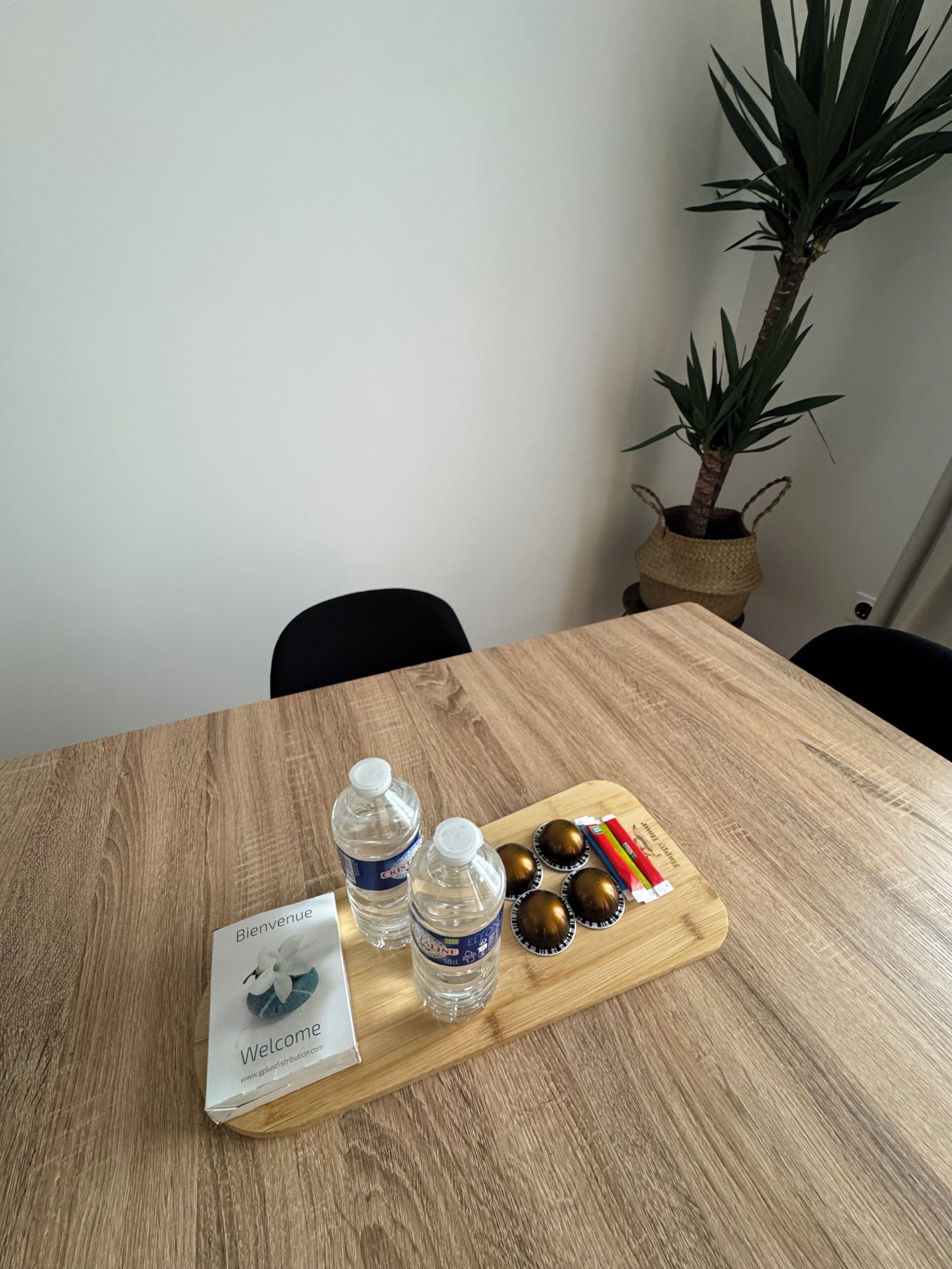 A wooden table with two water bottles, a welcome box, and a tray with snacks.