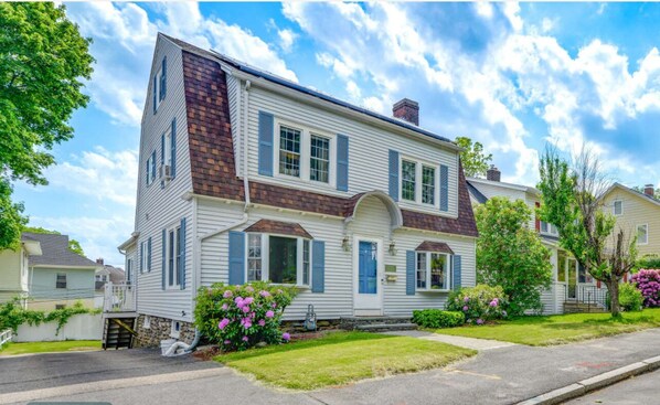 A two-story house with a gabled roof, a front porch, and a brick chimney.