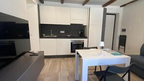 Une cuisine compacte avec des meubles blancs, un plan de travail noir et un four encastré.