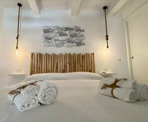 A modern bedroom with a wooden headboard, two bedside tables, a large bed, and decorative wall art. - La Maschera Apartments - Historic Center of Tropea (Tropea)