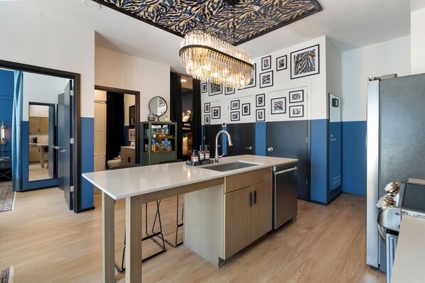 A modern kitchen with a central island, stainless steel appliances, and a decorative chandelier.