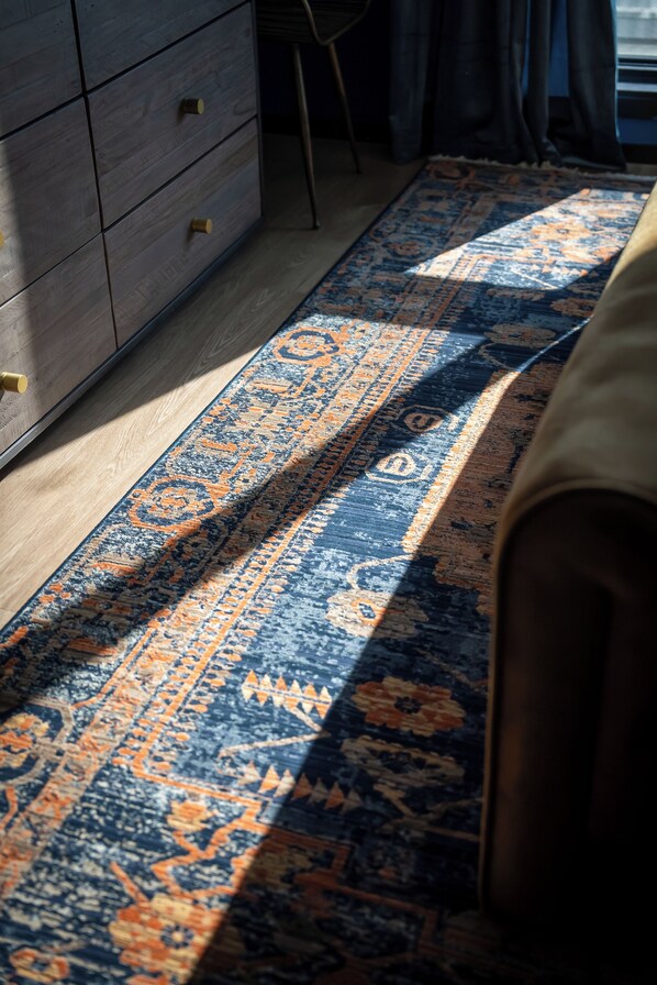 Una habitación con un aparador de madera, una alfombra estampada y una silla.