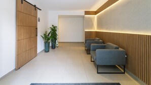 A modern waiting area with a sliding door, seating, and potted plants. - Residencial Pacobá (São Paulo)
