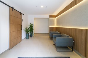 A modern waiting area with a sliding door, seating, and potted plants. - Residencial Pacobá (São Paulo)