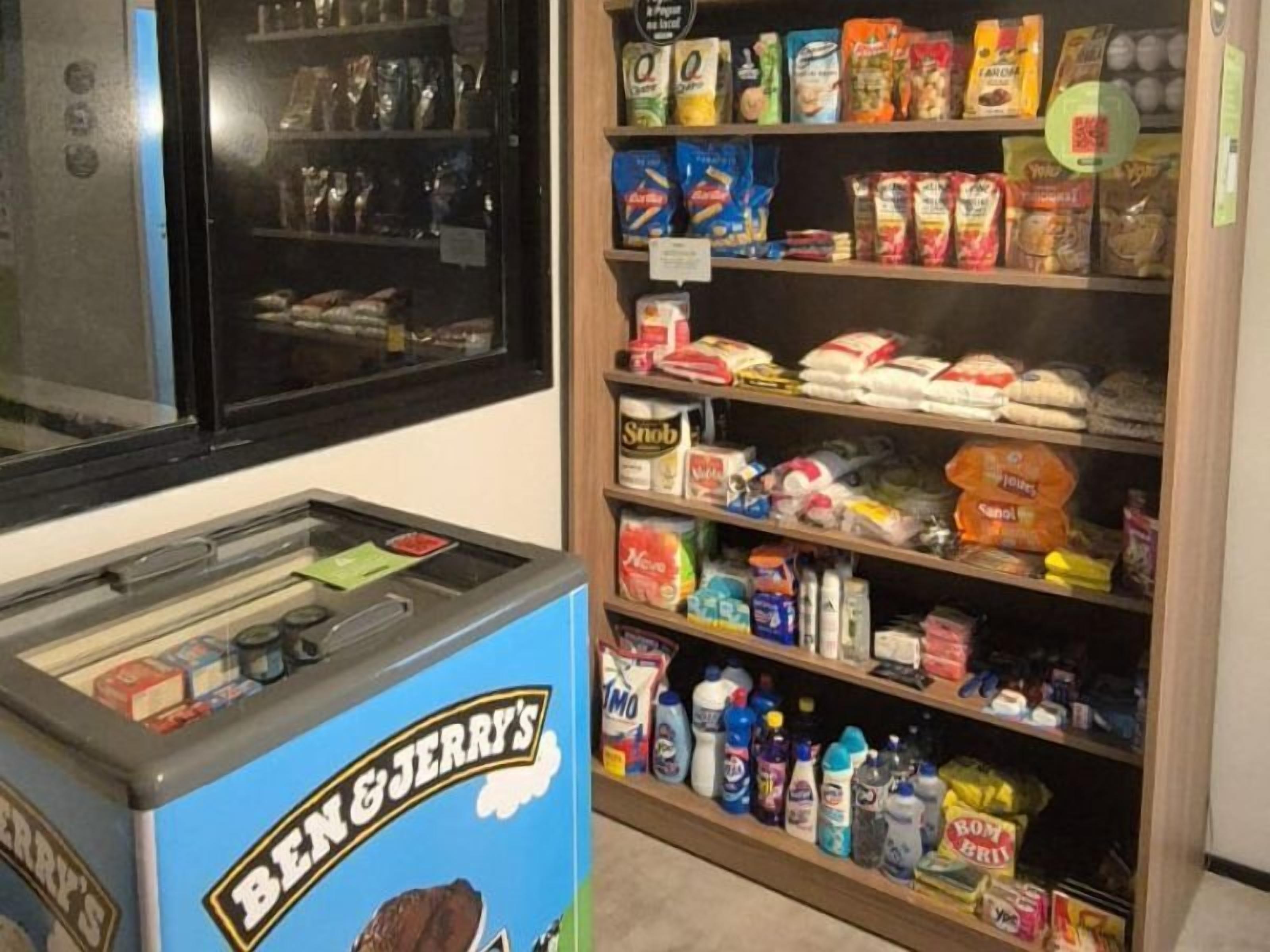 Ein Verkaufsautomat mit der Aufschrift 'BEN & JERRY'S' und Regalen voller verschiedener Snacks und Haushaltsartikel.