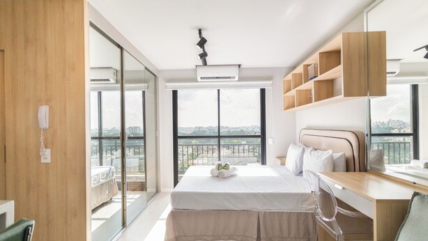 Una camera da letto moderna con un letto grande, una scrivania e un balcone con vista sulla città.