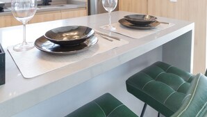 Una cucina moderna con isola centrale, elettrodomestici in acciaio inossidabile e sgabelli da bar verdi.