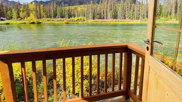 A wooden deck with a view of a lake, trees, and mountains. - Black Bear, Black Bear Lakefront Cabin (Cantwell)