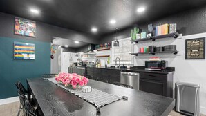 Une cuisine moderne dotée d’un îlot central, de meubles de couleur noire et d’appareils électroménagers en acier inoxydable.
