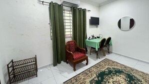 Een kamer met een eettafel, stoelen, een houten stoel, een klein plankje, een spiegel en een kamerkleed met een patroon.