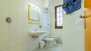 Ein Badezimmer mit Waschbecken, zwei Toiletten, einem Spiegel und einem Fenster.