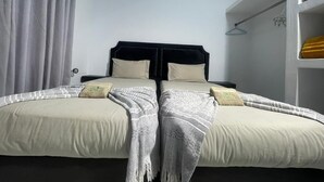 Un lit double avec une tête de lit noire, deux oreillers et une couverture.
