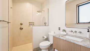 A modern bathroom with a glass-enclosed shower, a toilet, and a vanity with a mirror.