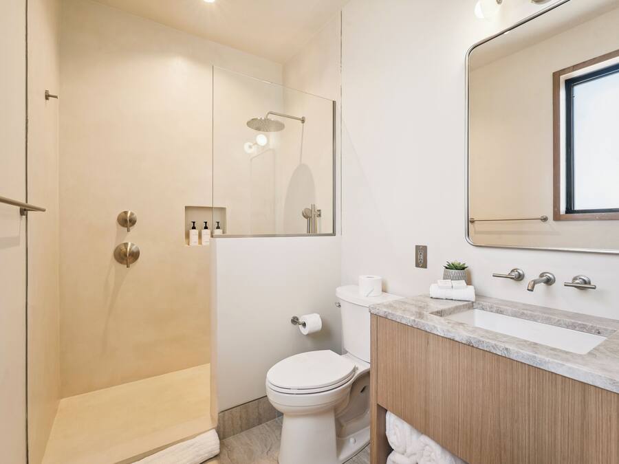 A modern bathroom with a glass-enclosed shower, a toilet, and a vanity with a mirror.