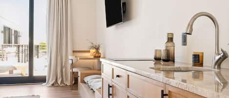 A modern kitchen with a large window, a flat-screen TV, and wooden cabinets.