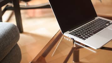 Ein Laptop auf einer Glastischplatte, im Hintergrund ein Stuhl.