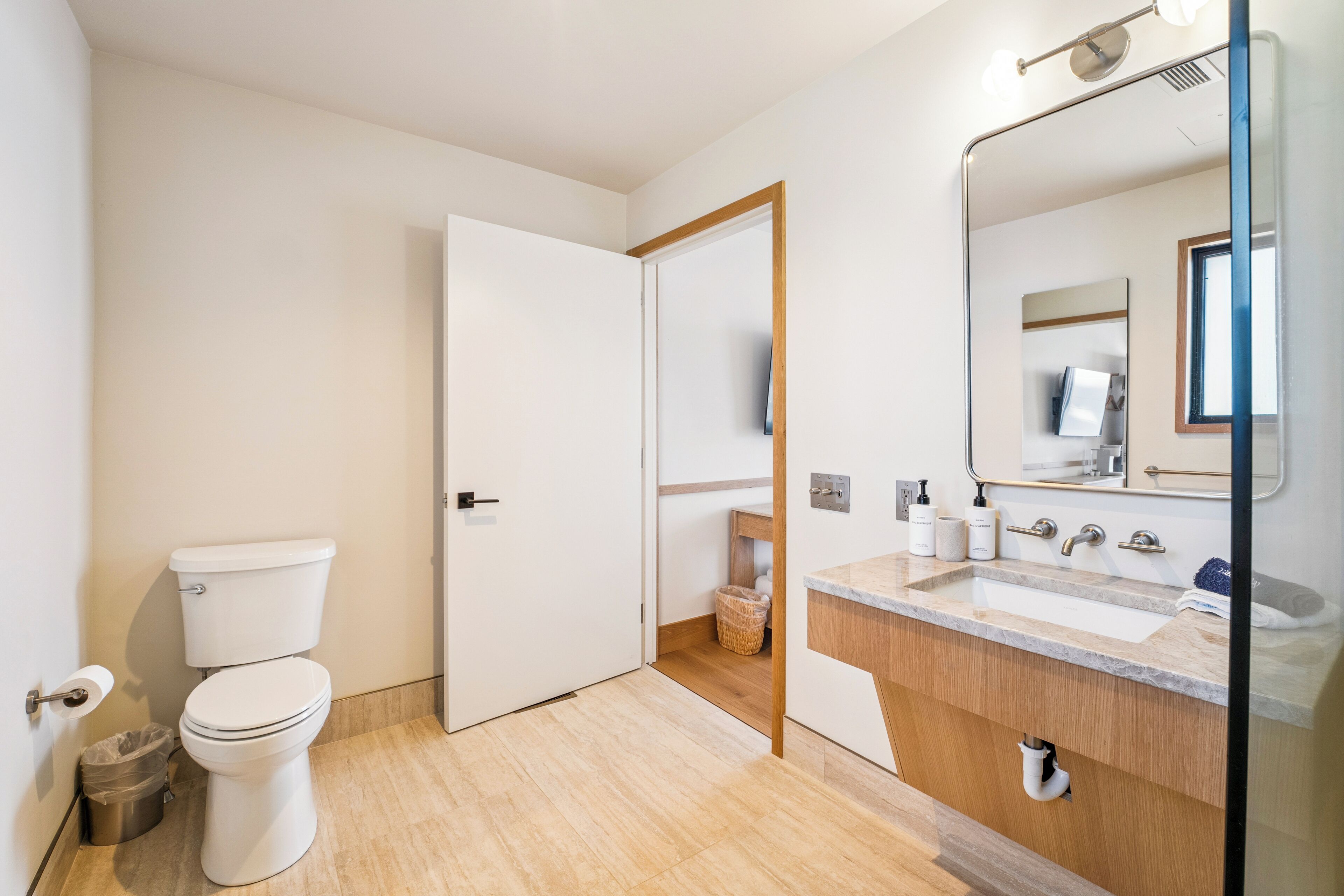 Un baño moderno con inodoro, lavamanos y espejo.