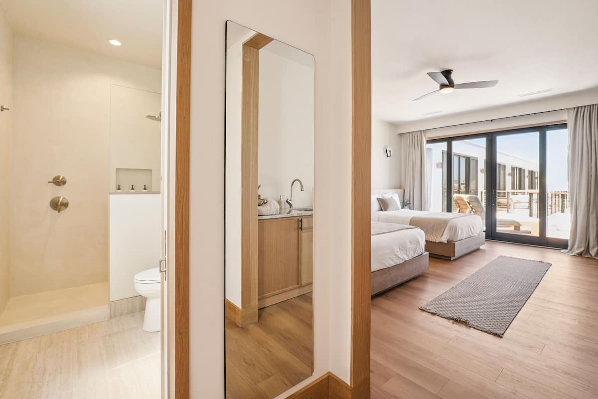 Une chambre d’hôtel moderne dotée d’une douche, de toilettes et d’un grand lit avec vue sur l’extérieur.
