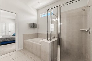 A modern bathroom with a glass shower enclosure, a bathtub, and a toilet.