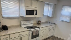 A kitchen with white cabinets, a microwave, an oven, and a countertop.