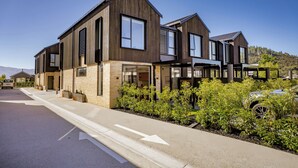 A modern two-story house with a driveway and a car parked nearby. - Explorers Rest - Wanaka Holiday Home (Wanaka)