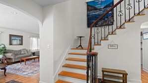 Una escalera de madera con barandilla de hierro forjado que lleva a un rellano con un cartel de bienvenida.
