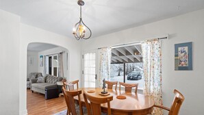 Un comedor con una mesa redonda de madera y sillas, un candelabro y vistas al exterior.