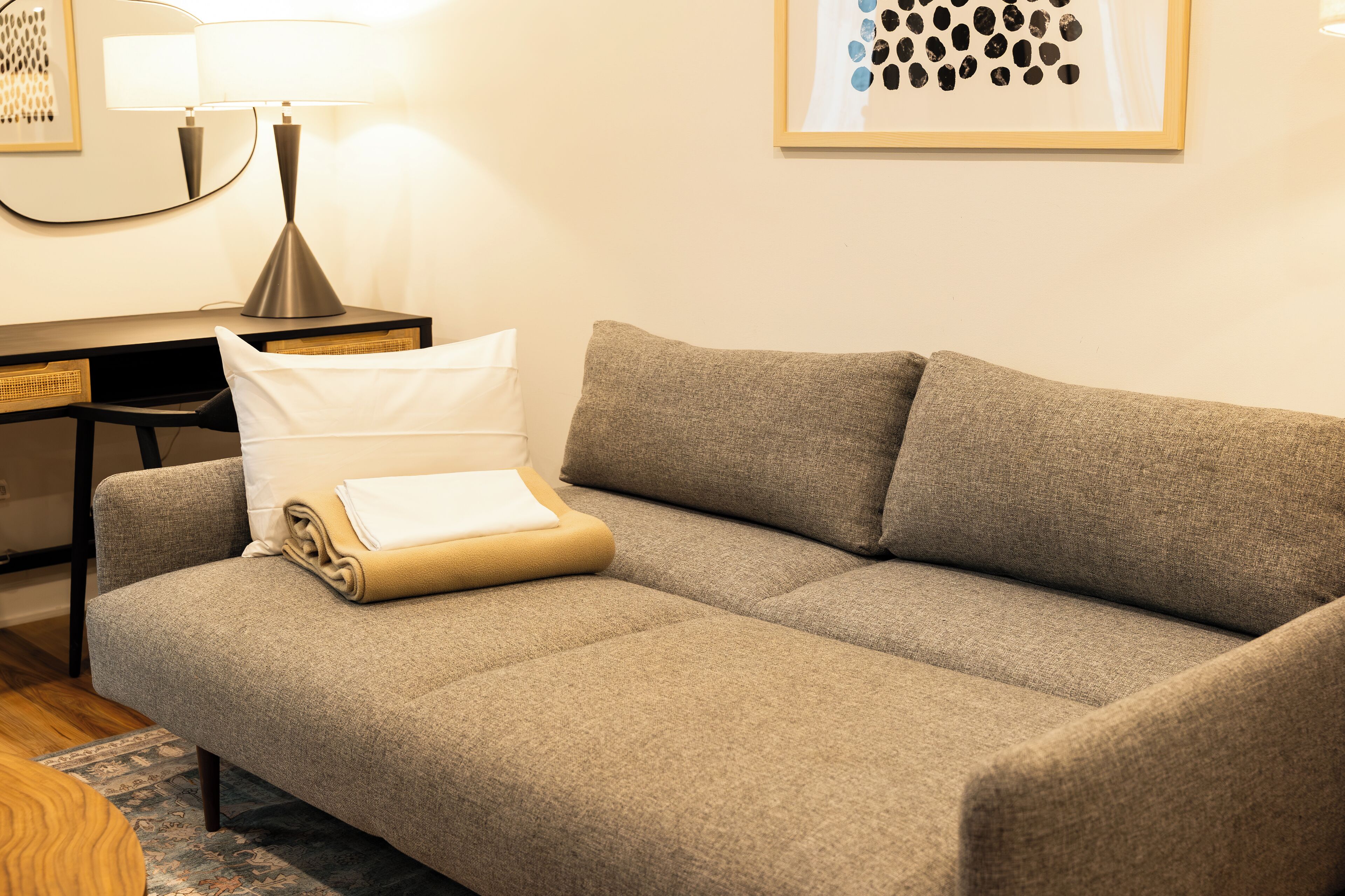 Ein modernes Wohnzimmer mit einer Couch, einer Lampe und einem gerahmten Kunstwerk an der Wand.