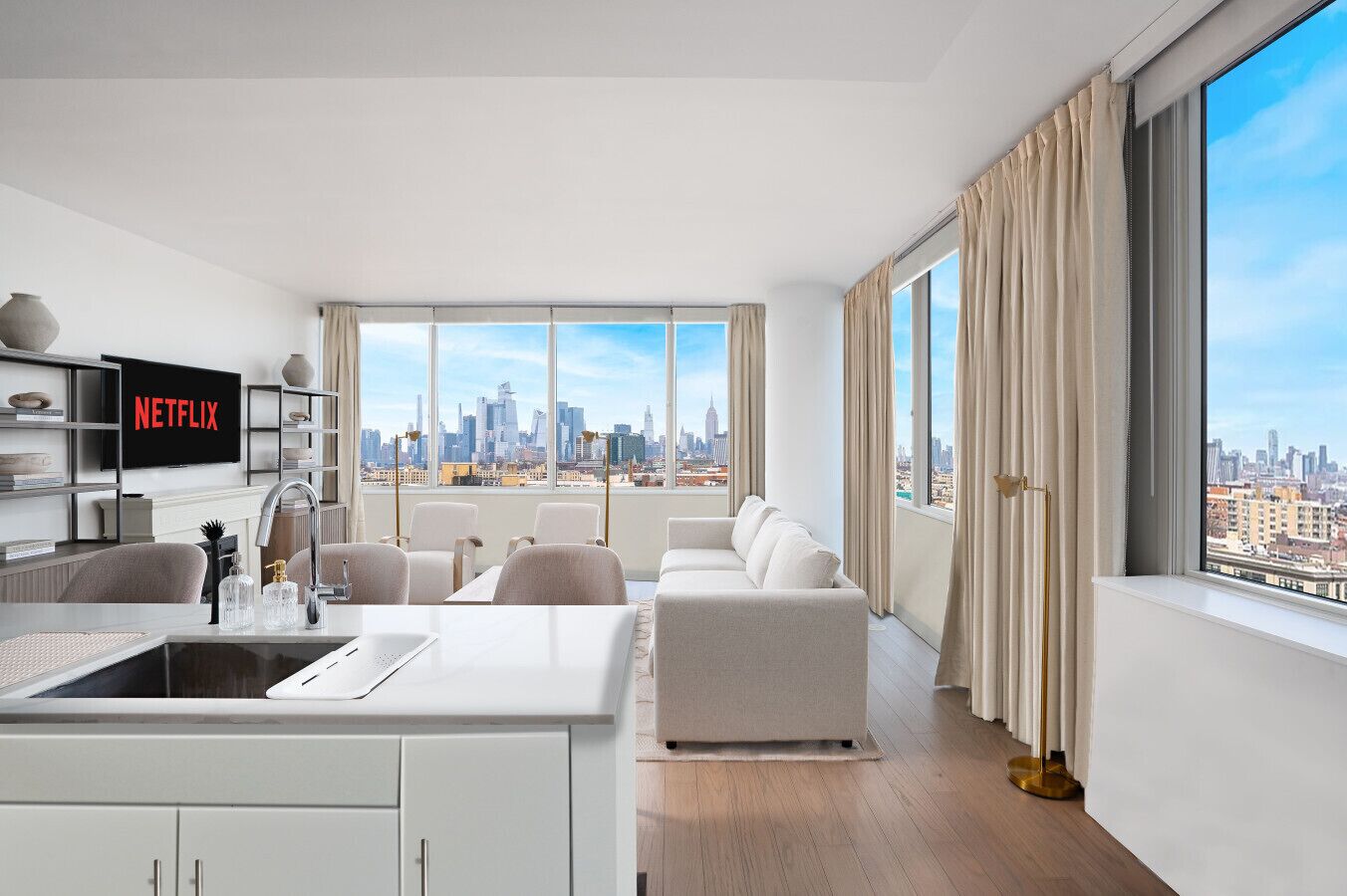 A modern living room with a city view, a kitchen area, and a flat-screen TV displaying 'NETFLIX'.