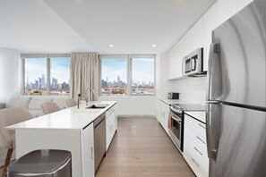 A modern kitchen with a large island, stainless steel appliances, and a city view.